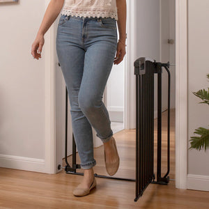Person wearing blue jeans and a white lace top stepping through a black pet gate.