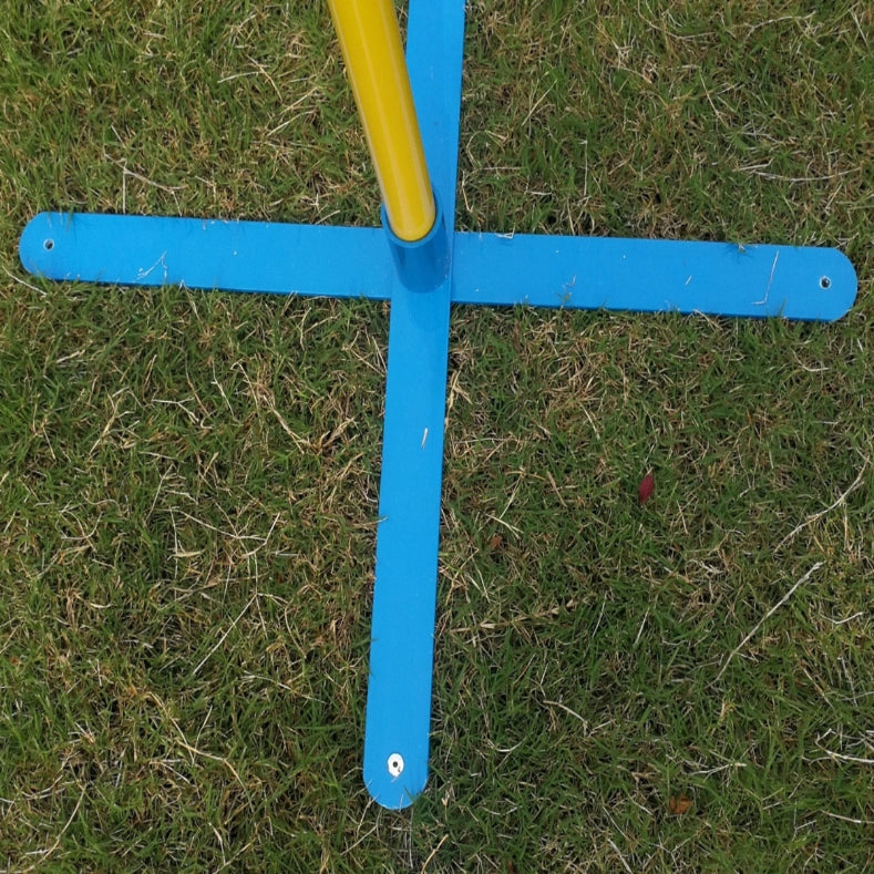A close-up of a blue cross-shaped metal frame with a yellow vertical pole, placed on a patch of green grass at Pet Servo