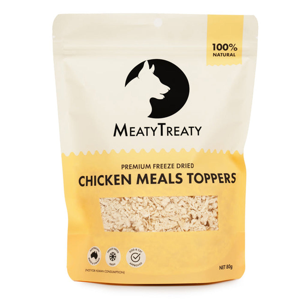 A stand-up pouch of MeatyTreaty Premium Freeze Dried Chicken Meals Toppers, featuring a cream and yellow packaging design with a black logo and a clear window showing the freeze-dried food inside.